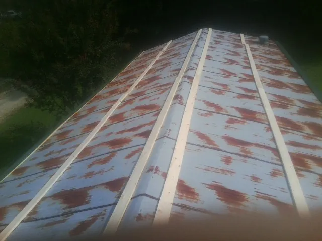 Rusted metal roof panels with new wood purlins before replacement in Rosalie