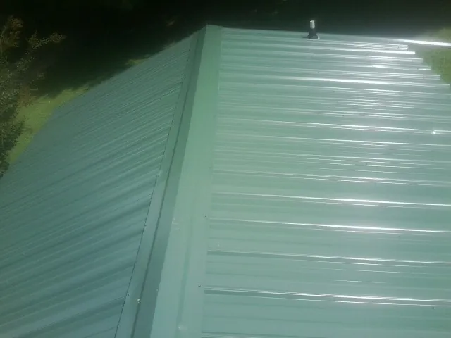 New green metal panels meeting at the ridge of a roof — Flat Roof Repair work by our crew in Rosalie