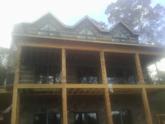 Dormers and porch framing on a large log home under construction — Roof Coating work by our crew in Rosalie