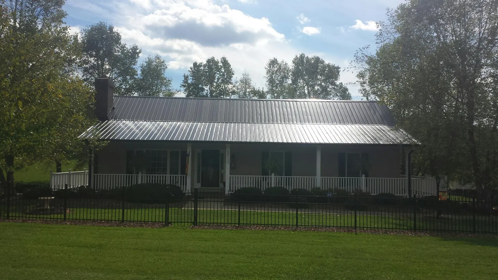 Gray metal roof on a brick ranch with a full width front porch — Gutter Guard Installation work by our crew in Rosalie