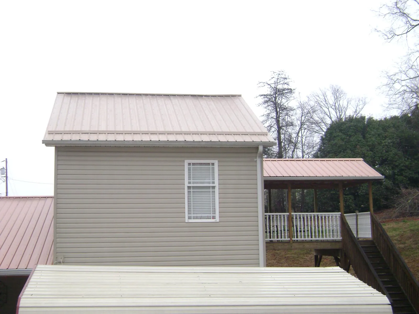 Tan metal roofs on a two story addition and attached porch, from a Roof Replacement job in Rosalie