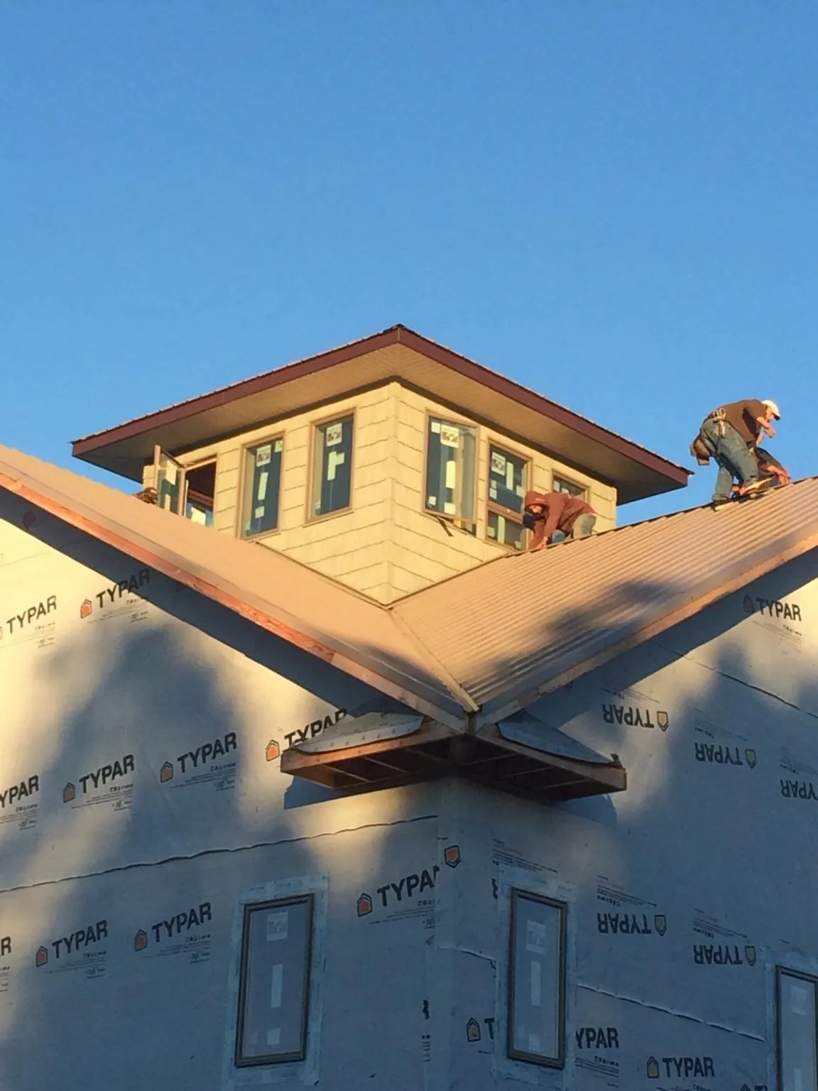 Roofers working around a rooftop cupola on a new metal roof at sunset — Roof Waterproofing in Rosalie by Roofing Brothers